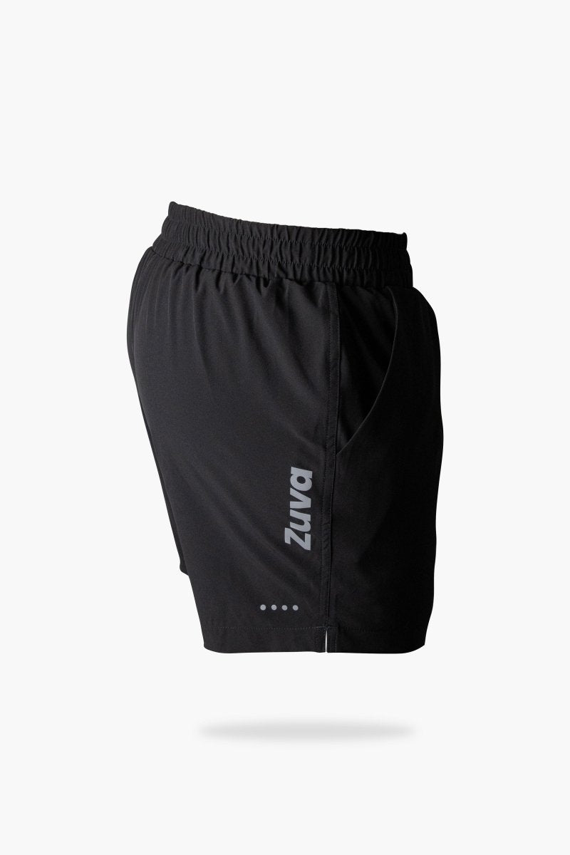 Side view of black men's athletic shorts featuring a vertical Zuva logo, elastic waistband, side pocket, and reflective detail near the hem.