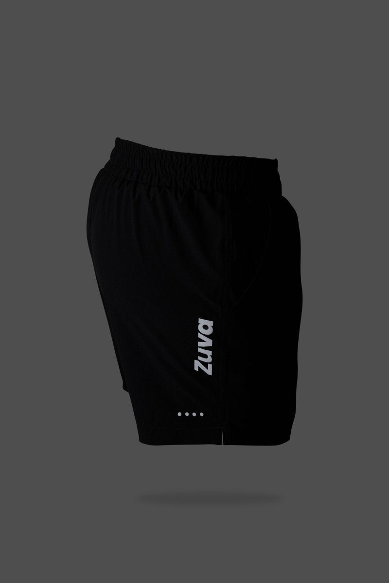 Side angled view of black athletic shorts with elastic waistband, Zuva-branded drawstrings, and reflective logo, set against a dark grey background for a premium aesthetic.