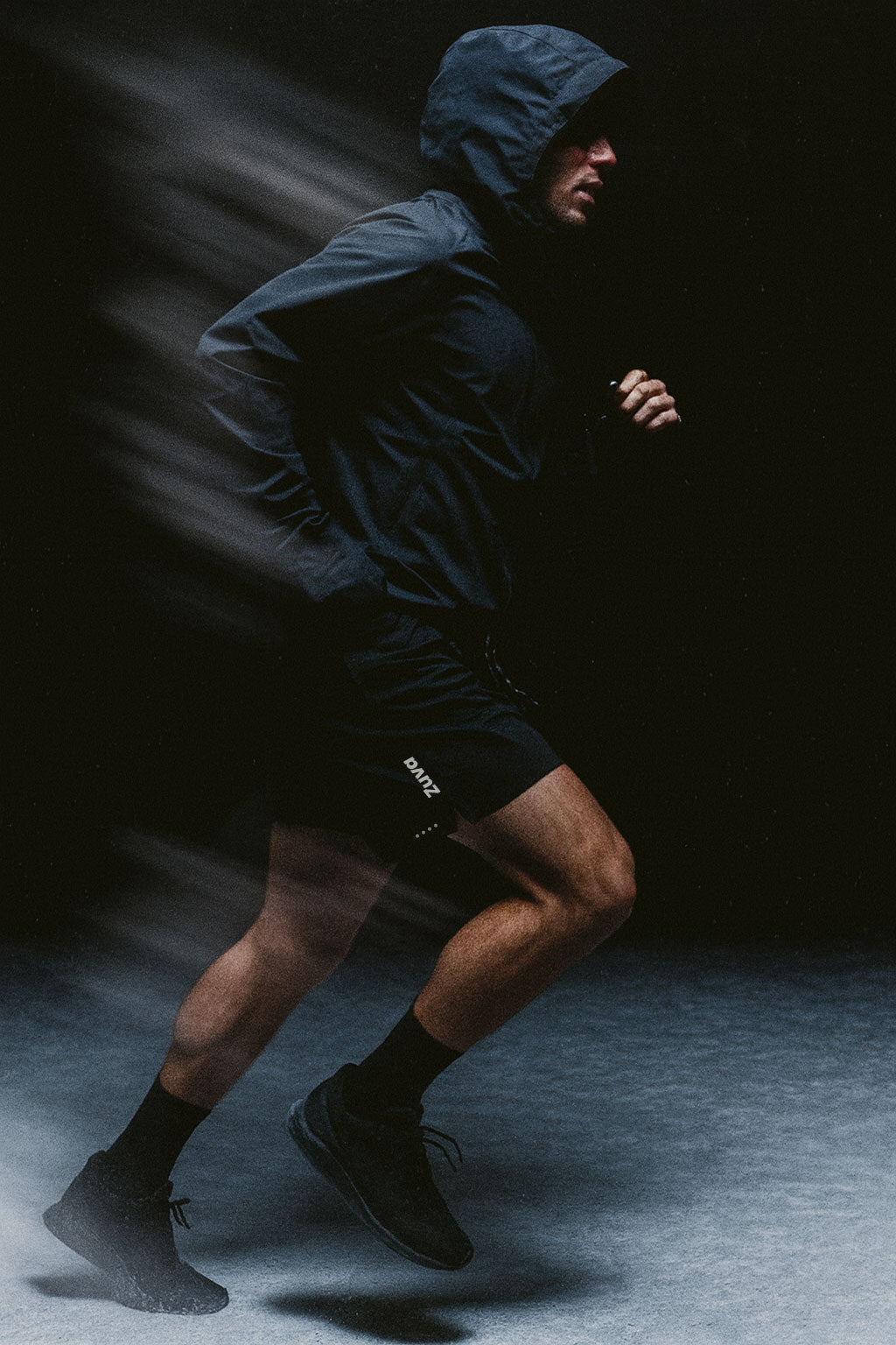 Male Athlete wearing a black jacket running in Zuva shorts