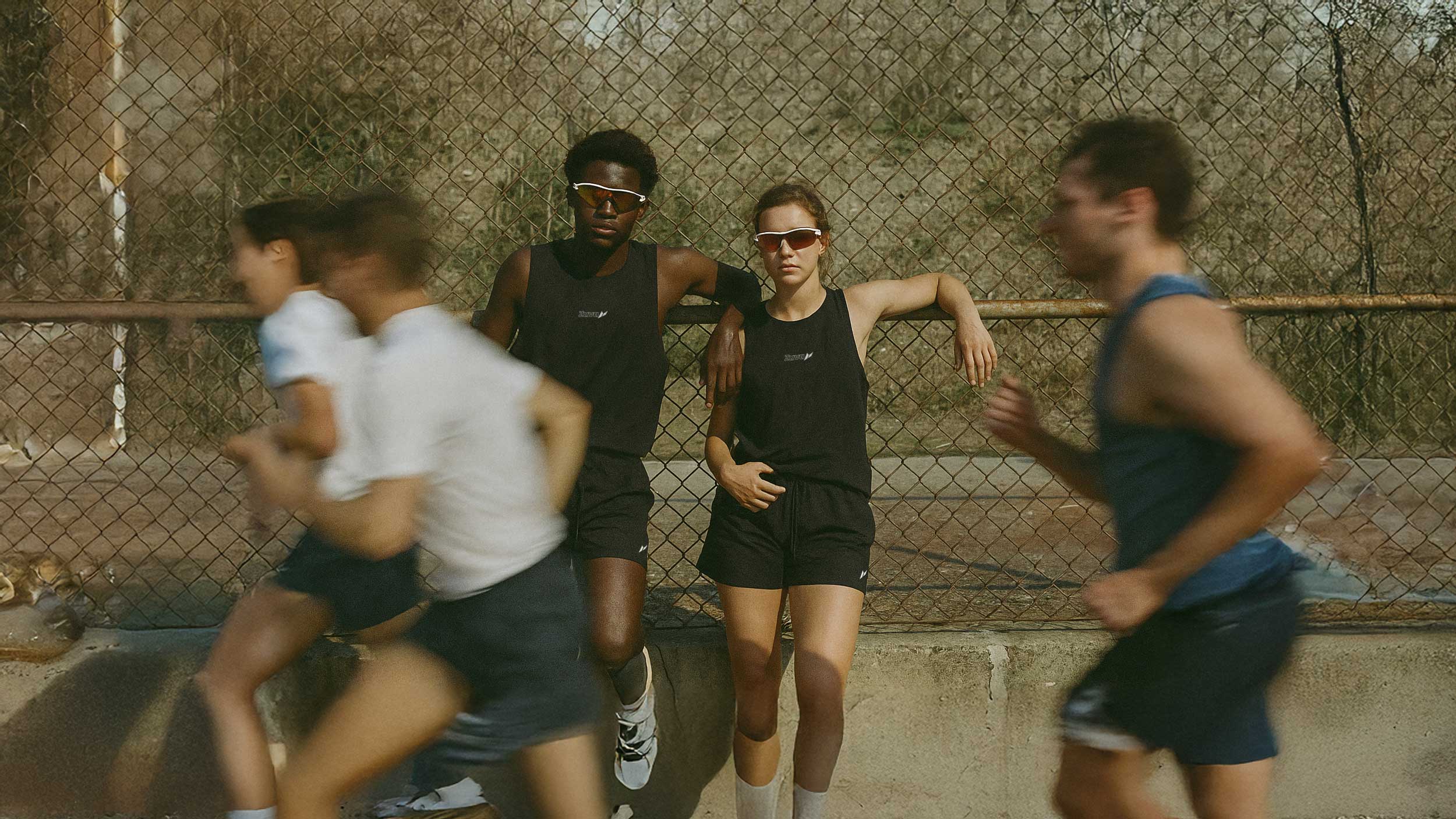 Male and female athlete standing on racetrack wearing zuva running gear