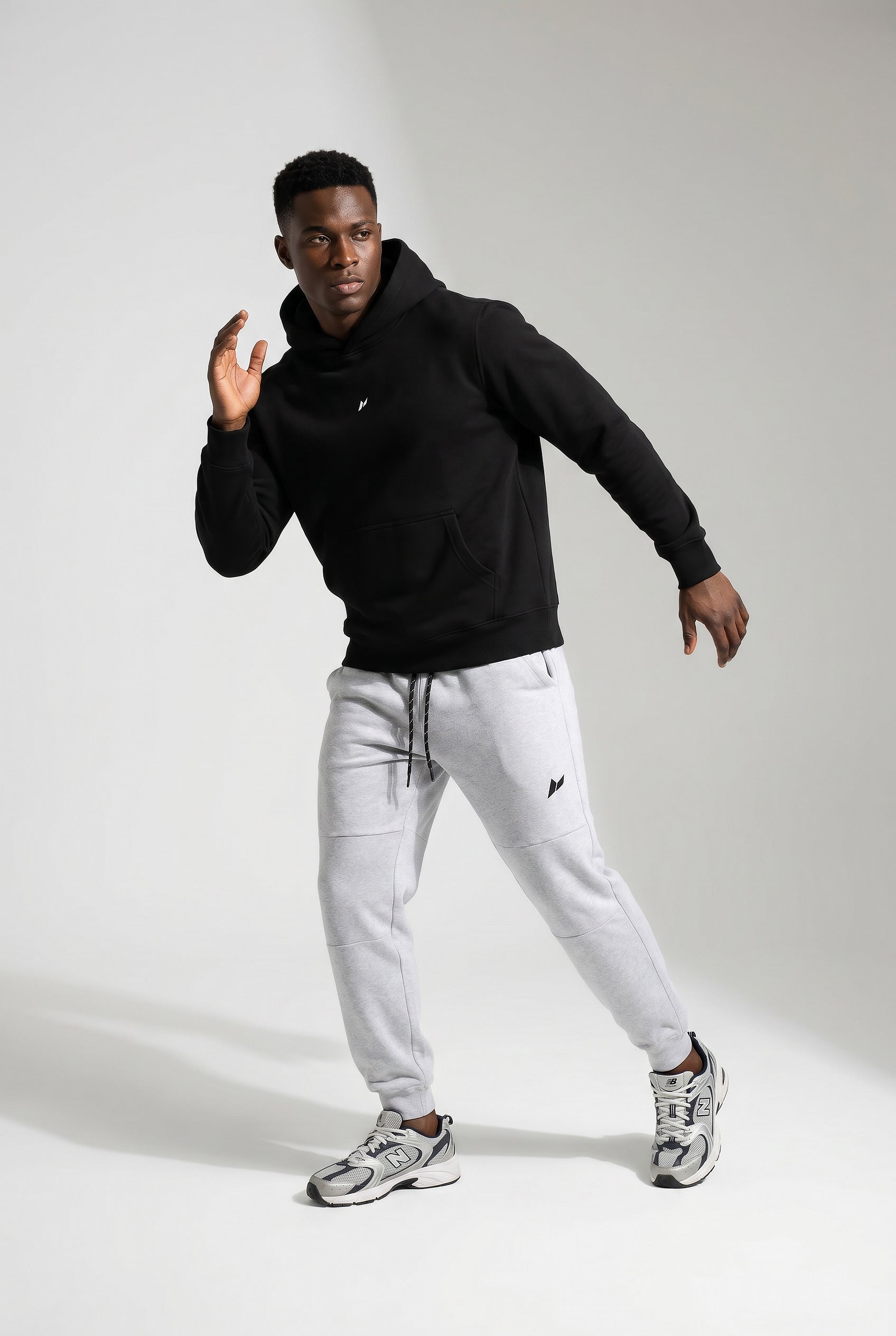 Male athlete wearing Zuva Black Hoodie and grey track pants gymwear Australia