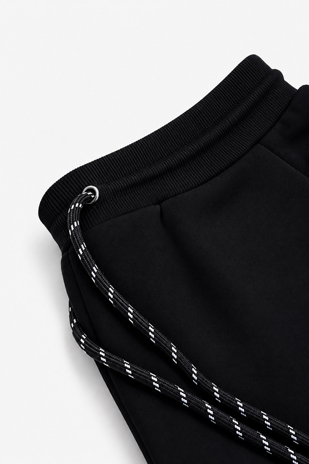Zuva Black Track Pants waistband detail close-up — ribbed black waistband with speckled black and white rope drawstring and silver eyelet hardware